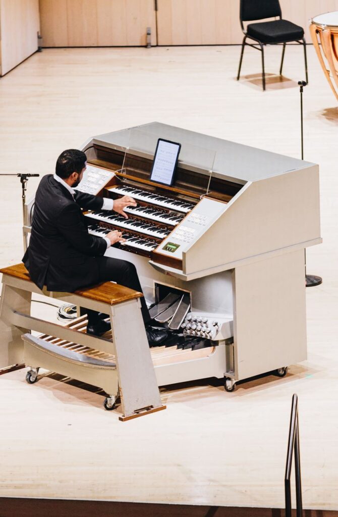 A man in a nice suit playing a moveable organ.