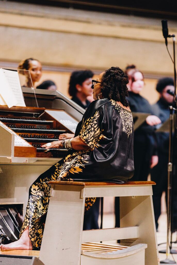 A woman playing the organ in front of a choir.