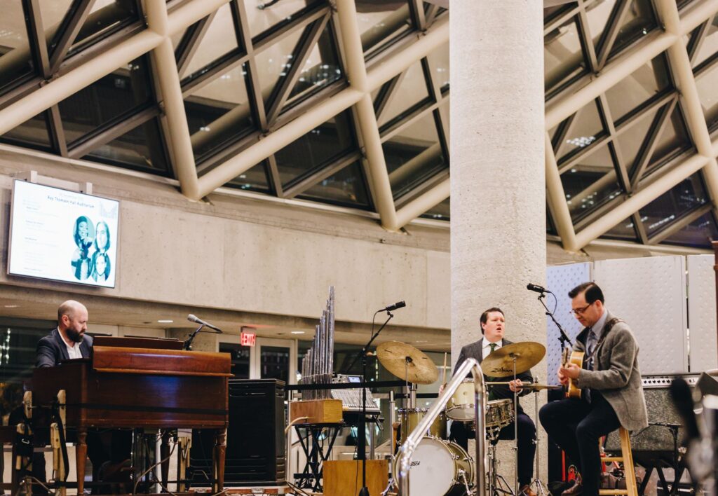 A trio of an organist, drummer, and guitar player on stage with their instruments.